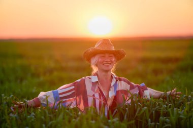Gün batımında buğday tarlasında orta yaşlı bir kadının portresi.