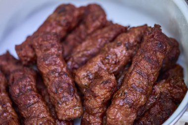 Mangalda mici ya da mititei denilen rulo köfteleri hazırlıyorum. Izgarayı alev ve dumanla yakın..