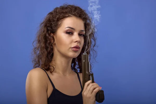 Hermosa Joven Con Pelo Rizado Con Una Pistola Sobre Fondo — Foto de Stock