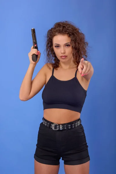 Vacker Ung Kvinna Med Lockigt Hår Med Pistol Blå Bakgrund — Stockfoto