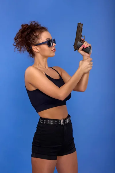 Vacker Ung Kvinna Med Lockigt Hår Med Pistol Blå Bakgrund — Stockfoto