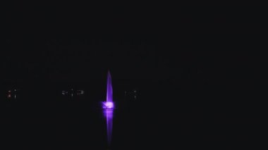 artesian fountain with lights on a lake at night