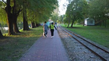 Köpekleri ile parkta yürüyen bir çift arkadan filme alınmış.