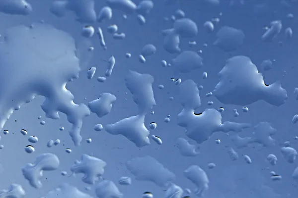 Gotas azuis frescas na superfície azul — Fotografia de Stock
