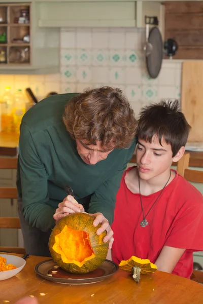 Far och son carving halloween pumpa på ett köksbord — Stockfoto