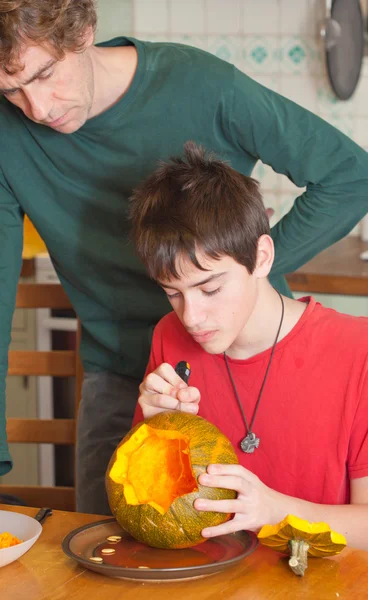 Father and son carving Halloween pumpkin on a kitchen table — Stock Photo, Image
