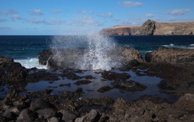 Gran Canaria, kuzey batı kıyısı doğal yüzme havuzları etrafında Salinas de Agaete, eski aşınmış karanlık lav platformuna karşı dalgalar kırılıyor.