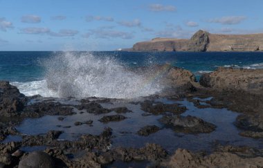 Gran Canaria, kuzey batı kıyısı doğal yüzme havuzları etrafında Salinas de Agaete, eski aşınmış karanlık lav platformuna karşı dalgalar kırılıyor.