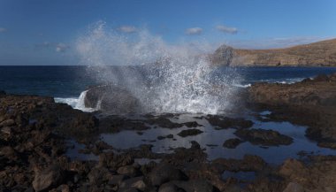 Gran Canaria, kuzey batı kıyısı doğal yüzme havuzları etrafında Salinas de Agaete, eski aşınmış karanlık lav platformuna karşı dalgalar kırılıyor.