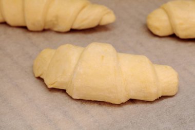 Parşömen kaplamalı fırın tepsisinde donmuş çiğ kruvasan.