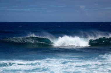 Gran Canaria, kuzey batı kıyısı doğal yüzme havuzları etrafında Salinas de Agaete, eski aşınmış karanlık lav platformuna karşı dalgalar kırılıyor.
