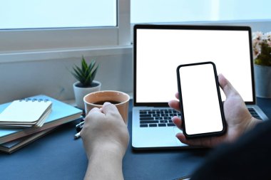 Kahve içen ve oturma odasında akıllı telefon kullanan bir adam..