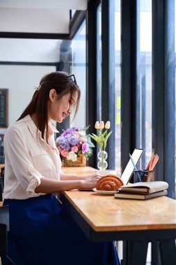 Kafede oturan ve bilgisayar laptopuyla çalışan serbest çalışan bir kadın..