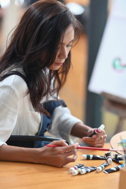 Yaratıcı bir sanat stüdyosunda resim yapan genç bir kadın sanatçı..