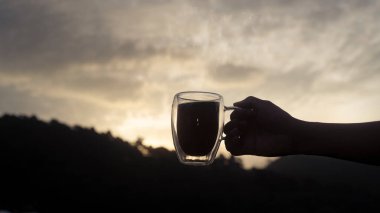 Arka planda güzel doğal dağ manzaralı kahve fincanı tutan adamın silueti..