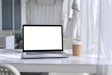 Rahat bir iş yerinde beyaz masadaki boş ekranla bilgisayar laptopunu düzenle.