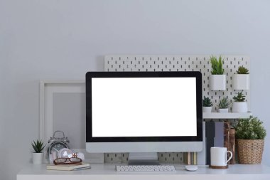 Ön görünüm boş ekran, kitaplar ve ev bitkisi ile beyaz masa üzerinde bilgisayarı taklit eder.