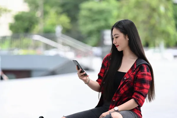 在城市里 年轻女人用智能手机坐在户外 — 图库照片