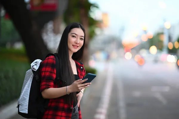 年轻女子站在街上时 在智能手机上使用出租车服务应用程序 — 图库照片