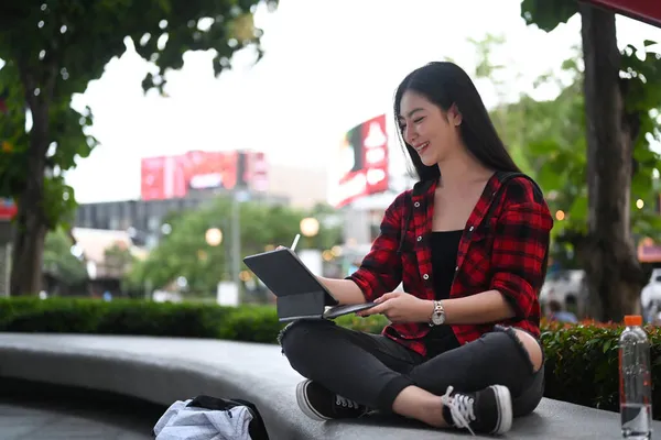一个快乐的女人坐在城市里 用数码平板电脑上网 — 图库照片