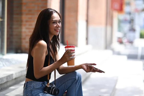 Gülümseyen Genç Kadın Dışarıda Oturmuş Elinde Buzlu Kahveyle Akıllı Telefon — Stok fotoğraf
