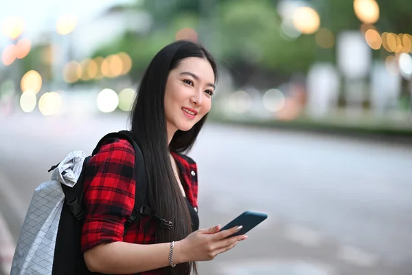 在智能手机上应用出租车服务应用程序对亚洲女性旅行者进行微笑 — 图库照片