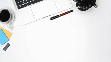 Laptop bilgisayarı, yapışkan notlar ve beyaz masada kahve fincanı olan basit bir iş yeri..