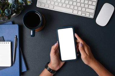 İş kadını siyah arka planda akıllı telefon kullanıyor.