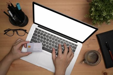Üst görüşlü erkek dizüstü bilgisayar kullanıyor. Alışveriş veya bankacılık için cep telefonu kullanıyor..