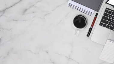 Bilgisayar dizüstü bilgisayar, not defteri ve kahve fincanı mermer masada..