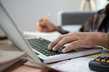 Bilgisayarı kullanan ve oturma odasındaki ev ekonomisini yöneten adamı kapat..