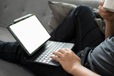 Yakın çekim adamım, kahve içiyor ve kanepede bilgisayar tableti kullanıyor..