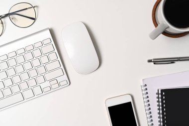 Akıllı telefon, kahve fincanı ve defterle üst kattaki ofis masasında..