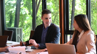 Toplantı odasında iş arkadaşlarıyla proje üzerinde çalışan yakışıklı bir iş adamı..