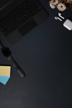 Üst görünüm akıllı saat, dizüstü bilgisayar ve siyah deri kulaklık..