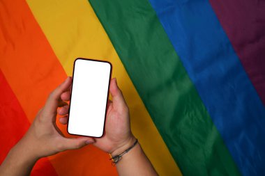 Adam elleri gökkuşağı arka planında beyaz ekranlı akıllı telefonu tutuyor.