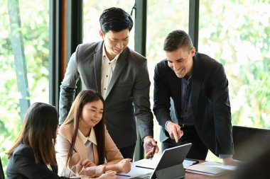 Çeşitli iş adamları toplantı odasında proje stratejisini tartışıyor.