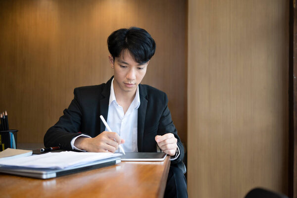 Бизнесмен сидит в своей офисной комнате и использует цифровой планшет.