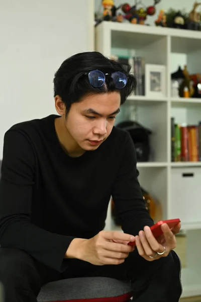 Νεαρός Που Χρησιμοποιεί Έξυπνο Τηλέφωνο Ενώ Κάθεται Στον Καναπέ — Φωτογραφία Αρχείου