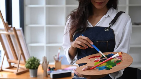 女性の笑顔創造的な職場に立っている間にパレット上の色を混合アーティスト — ストック写真