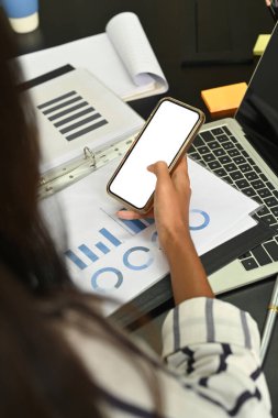 Kırpılmış iş kadını masasında oturuyor ve akıllı telefon kullanıyor..