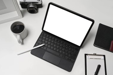 Bilgisayar tabletini, kahve fincanını ve kamerayı beyaz masaya yerleştir..