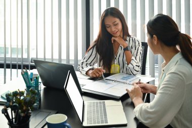 Genç iş arkadaşları ofiste çalışmayı tartışıyor..