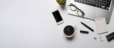 Üst görünüm bilgisayar dizüstü bilgisayar, akıllı telefon, kahve fincanı ve beyaz masadaki defter..