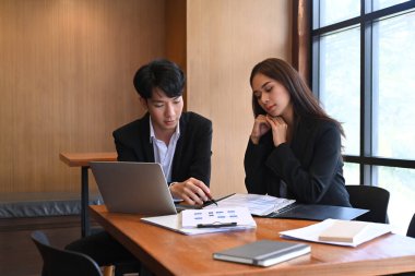 Modern işyerinde proje planlama ve paylaşma fikrini tartışan iki iş arkadaşı.