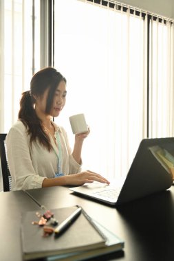 Kahve içen ve dizüstü bilgisayardaki e-postaları kontrol eden güzel iş kadını..
