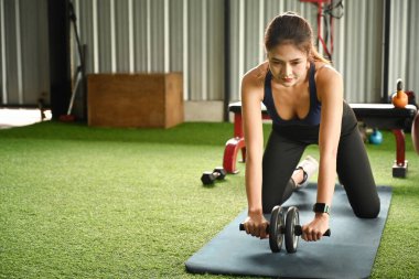 Sporcu kadın spor salonunda karın silindiri ile çalışıyor..