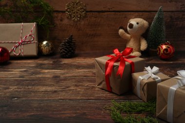 Hediye kutuları, oyuncak ayı, çam kozalakları ve ahşap masadaki köknar dalları..