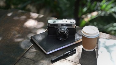 Boş ekranlı dizüstü bilgisayar, kahve fincanı ve açık kafedeki ahşap masada defter..