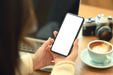 Omzunun üstünden bak. Akıllı telefonu boş bir ekranla tutan genç kadın..